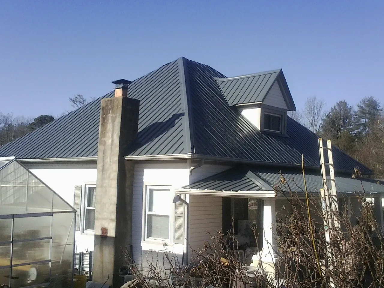 Dark blue standing seam metal roof on a white farmhouse with dormer — Slate & Tile Roof Repair by Roofing Brothers in Summitville