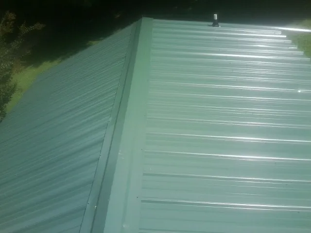 New green metal panels meeting at the ridge of a roof in Summitville