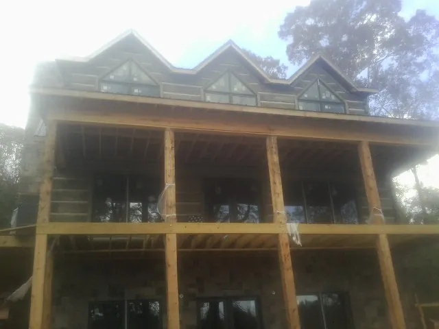 Dormers and porch framing on a large log home under construction — Roof Coating work by our crew in Summitville
