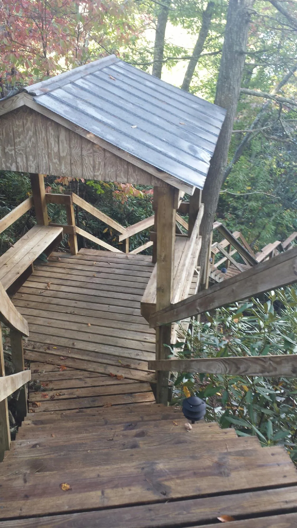 Metal roofed shelter over wooden steps on a wooded walkway — Skylight Repair & Installation work by our crew in Summitville