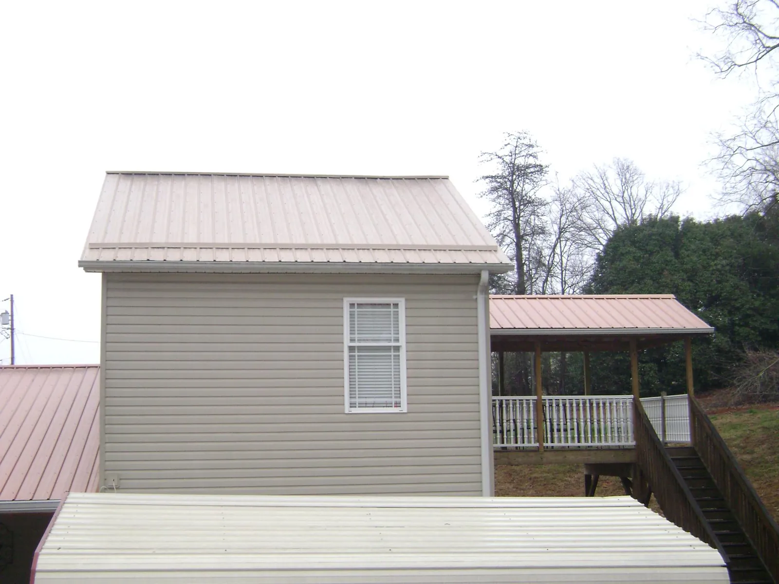 Tan metal roofs on a two story addition and attached porch, from a Roof Replacement job in Summitville