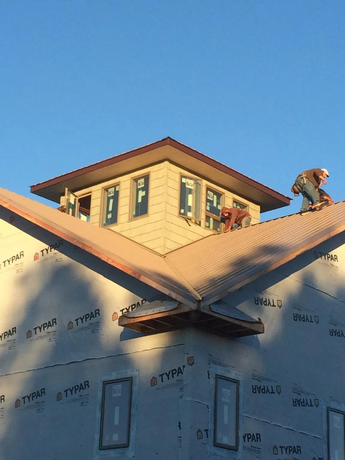Roofers working around a rooftop cupola on a new metal roof at sunset — Roof Waterproofing in Summitville by Roofing Brothers